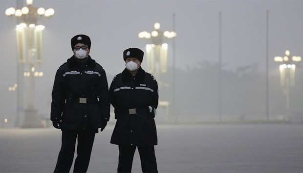 Policemen wear protective masks at the Tiananmen Square as choking smog continues to blanket Beijing