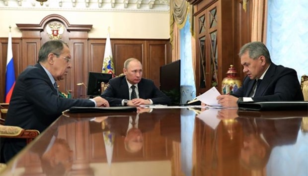 Russian President Vladimir Putin speaks with Defence Minister Sergei Shoigu (R) and Foreign Minister Sergei Lavrov (L) during their meeting at the Kremlin in Moscow on Thursday.