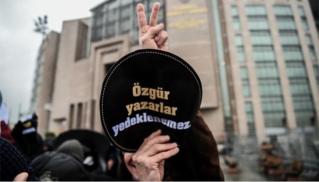 A man holds a sign meaning ,Writers' freedom is not guaranteed, outside Istanbul's courthouse on Thursday before the start of the trial of Turkish novelist Asli Erdogan.