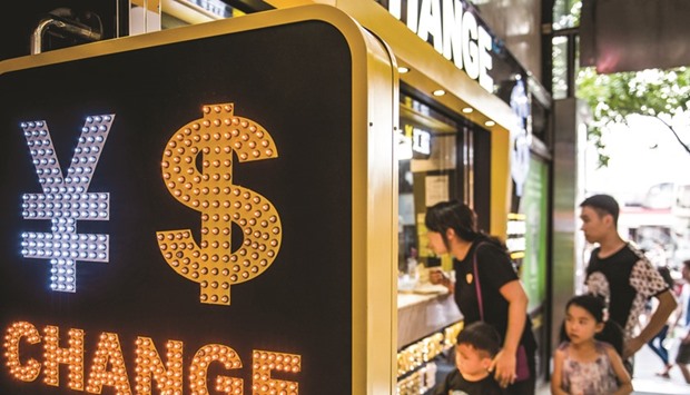 The currency symbol for the Chinese yuan and the US dollar is displayed at a currency exchange store in Hong Kong. The weighting of the dollar will fall to 22.4% from 26.4% in a trade-weighted foreign-exchange basket from January 1, the China Foreign Exchange Trade System said in a statement yesterday.
