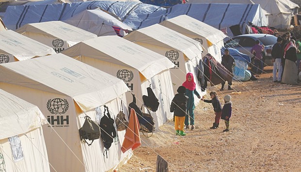 Evacuees from a rebel-held area of Aleppo stand near their tents in al-Kamouneh camp, Idlib province, Syria yesterday.
