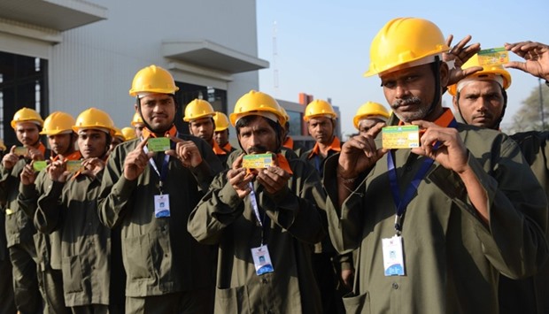Indian workers pose with their bank debit cards before work at a heavy fabrication manufacturing factory in Vasna Buzarg village, some 40 kms from Ahmedabad.