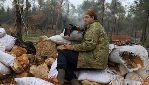 A rebel fighter rests with his weapon behind sandbags at insurgent-held al-Rashideen, Aleppo province on Friday.