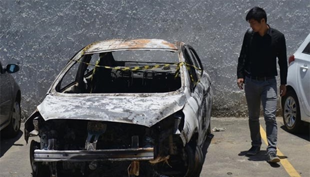 A man looks at the burned-out rental car of missing Greek ambassador to Brazil Kyriakos Amiridis in Belford Roxo, in the Brazilian state of Rio de Janeiro, on Friday, a day after it was found with a body inside.