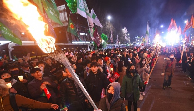 Protesters carry torches as they march toward the presidential Blue House during a rally against South Korea's President Park Geun-Hye in central Seoul .