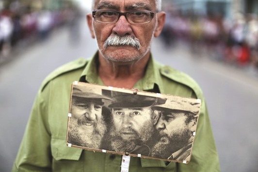 Eliberto Miniti holds photographs of Cubau2019s former president Fidel Castro as he waits for Castrou2019s ashes to pass during a three-day journey to the eastern city of Santiago de Cuba.