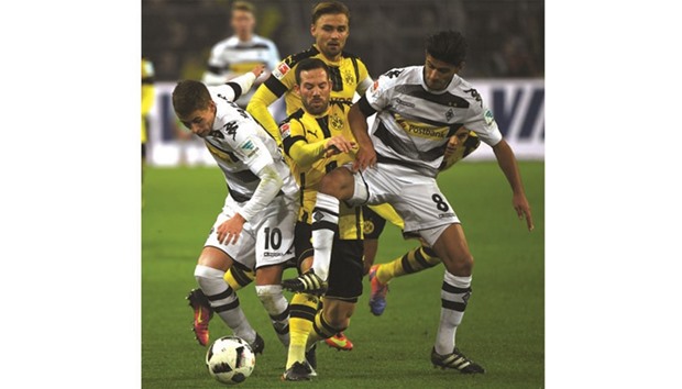 Dortmundu2019s Gonzalo Castro (centre), Moenchengladbachu2019s Thorgan Hazard (left) and Mahmoud Dahoud fight for the ball during the Bundesliga match at the Signal-Iduna-Park in Dortmund, western Germany, yesterday. (AFP)