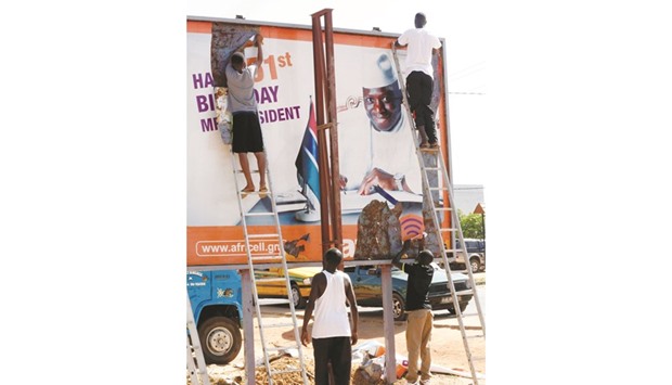 People begin removing an election poster for Jammeh in Broussbi, Gambia.