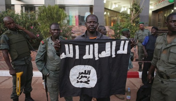 Malian security officials display the flag of a militant group they said belonged to attackers in front of the Radisson Blu Hotel in Bamako, Mali, November 20, 2015