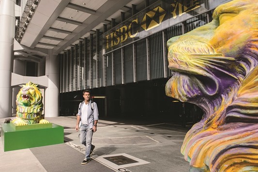 A man walks between a pair of lions painted in rainbow stripes displayed outside HSBCu2019s main office in Hong Kong.