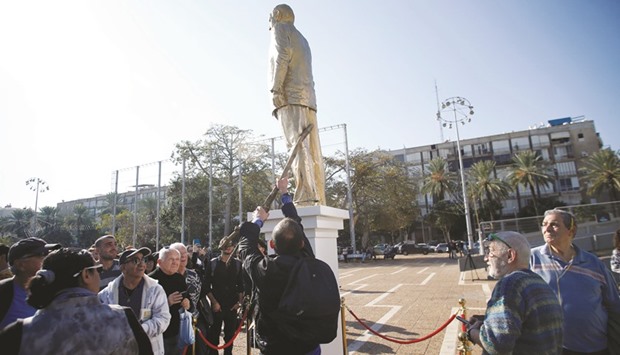 A man in the crowd uses a stick to topple over a statue of Israeli Prime Minister Benjamin Netanyahu, created by Israeli sculptor Itay Zalait as a political protest against Netanyahu, at a square outside Tel Avivu2019s city hall, yesterday.