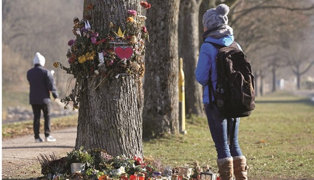 A woman looks at flowers and messages attached on a tree near the site in Freiburg where a 19-year-old female student died on October 15.