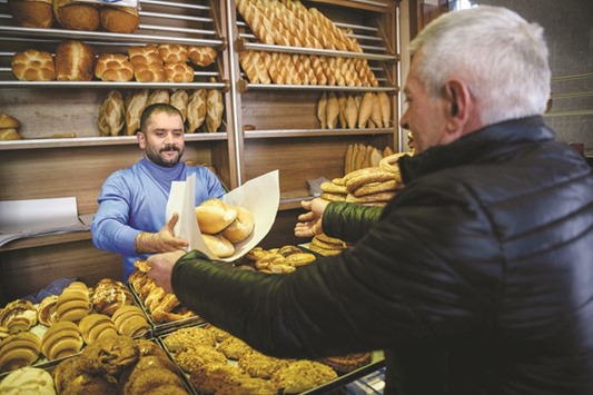 A customer takes his free bread after showing a dollar exchange receipt to a shopkeeper in Istanbul yesterday. Barbers, restaurants, gold sellers and stonemasons were among those who responded to Erdoganu2019s call by offering free goods and services to citizens with proof for having converting their dollars to lira.