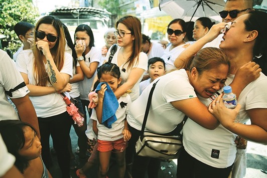 File photo shows the wife and other relatives of Florjohn Cruz, who was killed in a police drugs buy-bust operation, cry as his coffin leaves their home for his funeral in Manila.