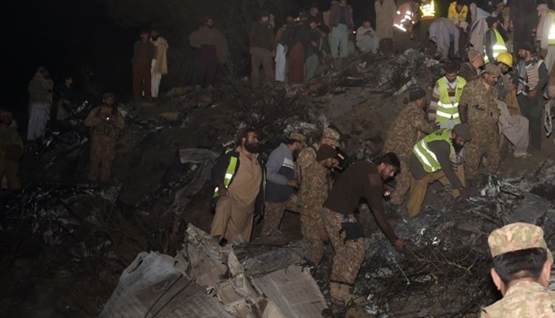 Pakistani soldiers and volunteers search for victims from the wreckage of the crashed PIA passenger 