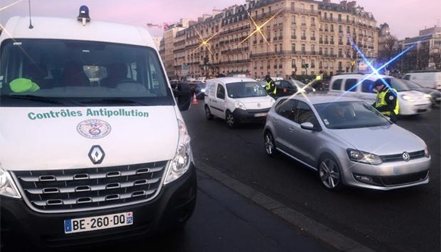 Traffic police control cars as they try to enforce the anti-pollution measures in Paris on Thursday. Paris was smothered on Wednesday by its worst winter pollution in a decade, with commuters enjoying free public transport and half of all cars ordered off the road to try to clear the air.