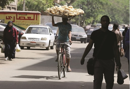 A bakery worker rides a bicycle as he carries fresh bread on his head in Cairo. Prices in the most populous Arab country were likely to keep rising next year, economists said, driven by recent reforms that have included subsidy cuts and tax increases.