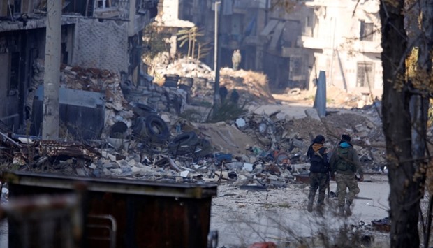 Forces loyal to syria's President Bashar al-Assad walk past damaged buildings in a government held area of Aleppo.