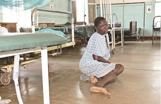 A patient sits on the floor alone, without medical carers who have gone on strike, at the Kisumu County Hospital in Kisumu, Kenya.