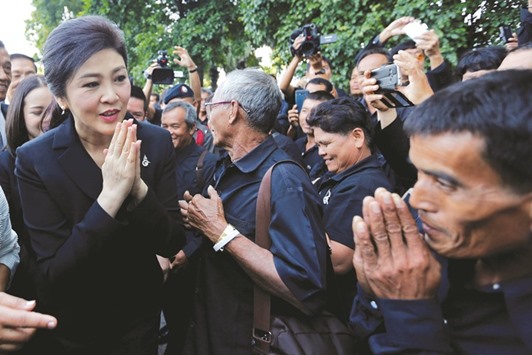 Ousted former Thai Prime Minister Yingluck Shinawatra greets supporters as she arrives at the Supreme Court for a trial on criminal negligence looking into her role in a debt-ridden rice subsidy scheme during her administration, in Bangkok yesterday.