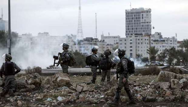 Israeli border policemen sweep an area past tear gas fumes during clashes with Palestinian protesters near an Israeli checkpoint in the West Bank city of Ramallah on Sunday. Unrest over US President Donald Trump's declaration of Jerusalem as Israel's capital has further complicated the process.