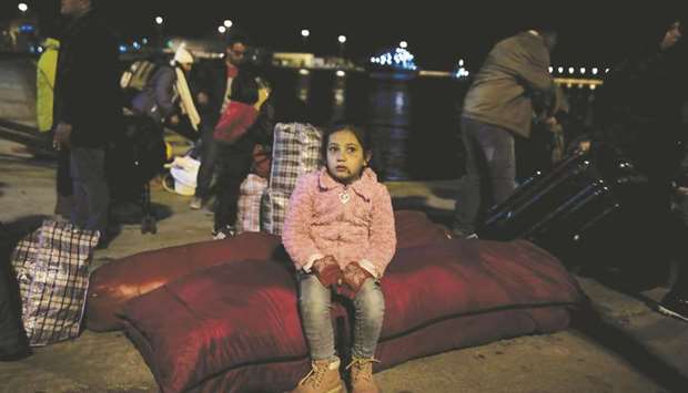 A child waits to board a bus following her arrival, on the passenger ferry Blue Star 2 from Lesbos, at the port of Piraeus, near Athens.
