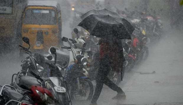 An Indian resident walks past under an umbrella during heavy monsoon rains in Chennai