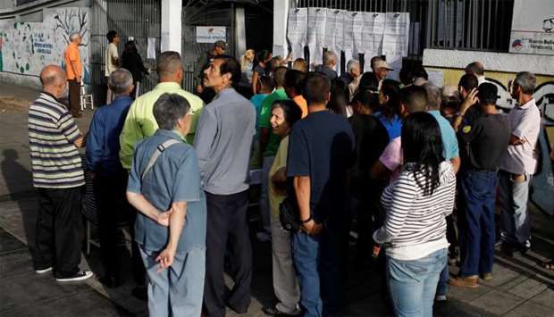People check a list at a polling station during a nationwide election for new mayors, in Caracas