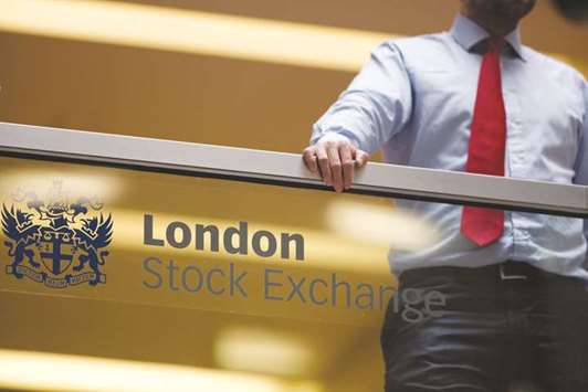 An employee leans on a glass wall above the main atrium of the London Stock Exchange Group headquarters. London stocks gained around 0.8% at 7,453.48 points yesterday.