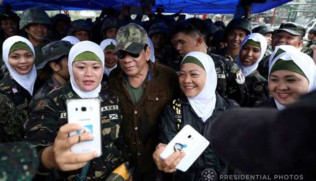 Philippine President Rodrigo Duterte (C) poses for a picture with female soldiers during his visit at Bangolo town in Marawi city, southern Philippines October 17, 2017