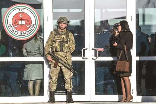 A woman stands at the entrance of the courthouse at Silivri district in Istanbul, as a Turkish soldier stands guard, on the opening day of the trial of an Uzbek citizen who confessed to killing 39 people at a nightclub.