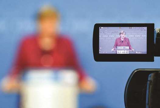 Merkel appears on a viewer of a camera as she addresses a press conference after a leadership meeting of her CDU party in Berlin.