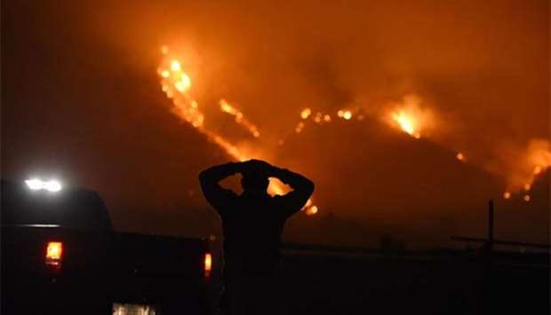 A man watches the Thomas Fire in the hills above Carpinteria, California.