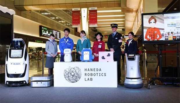 Haneda Airport employees pose with robots during a press briefing in Tokyo on Tuesday.