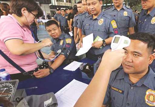 A nurse checks the temperature of a policeman who was vaccinated with Dengvaxia in September.
