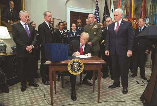 President Donald Trump, surrounded by military officials and members of Congress, signs H R 2810, National Defence Authorisation Act for fiscal year 2018, during a signing ceremony in the Roosevelt Room at the White House in Washington, DC, yesterday.