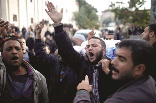 Mourners chant slogans as they carry the body of a Palestinian during his funeral in Gaza City yesterday.