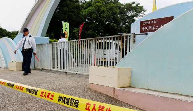A Japanese policeman stands guard at the entrance gate of the elementary school in Ginowan, Okinawa on December 13, 2017, where a window from a US military helicopter fell onto the school's sports ground.