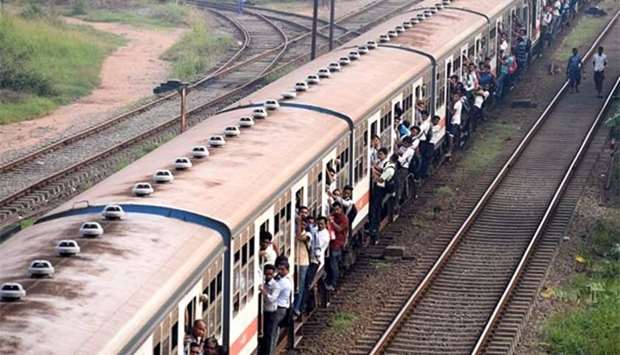 Sri Lankan passengers hold on to door handles as they travel on overfilled train carriages during a nationwide railway strike in Colombo on Wednesday.