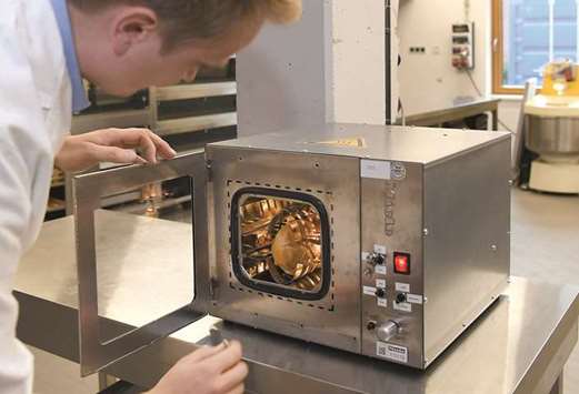ADVANCED TECH: Food technician Malte Gerken puts a bit of bread into a high-tech piece of baking machinery designed for use in space.