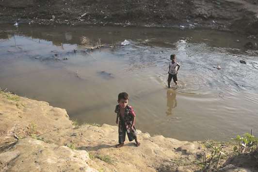 Two Rohingya refugee boys cross a stream from no-manu2019s land to Bangladesh, at the Bangladesh-Myanmar border.