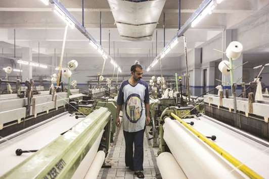 A worker inspects fabric on looms at a textile manufacturer in Karachi. The Pakistan government would continue with fiscal consolidation without taking steps to affect economic growth that was targeted at 6% may stay little lower, Secretary Finance Shahid Mahmood said yesterday.