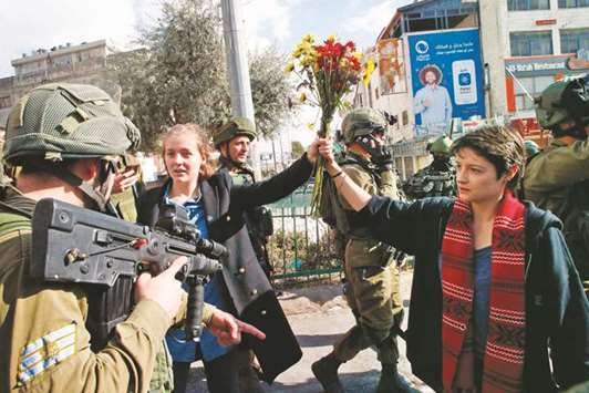 Members of the Israeli security forces confront French female demonstrators carrying a bouquet of flowers during a protest in the city centre of the occupied West Bank town of Hebron.