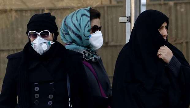 Iranian women wear face masks at a bus stop in Tehran as heavy pollution hit new highs in the capital