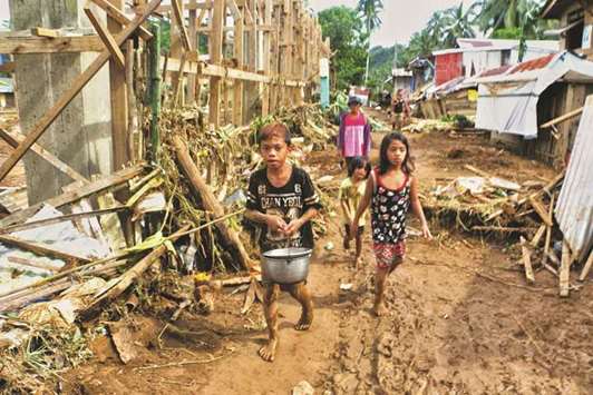 Children walk past damaged houses and fallen trees in Barangay San Mateo Borongan in eastern Samar yesterday, after Tropical Depression Kai-Tak blew through the area.