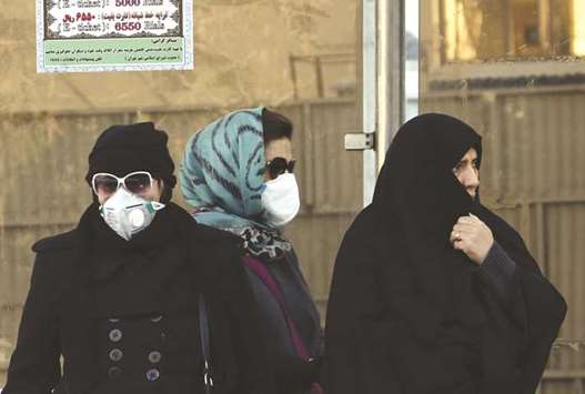 Iranian women wearing face masks wait at a bus stop as winteru2019s heavy pollution hit new highs in Tehran, yesterday.