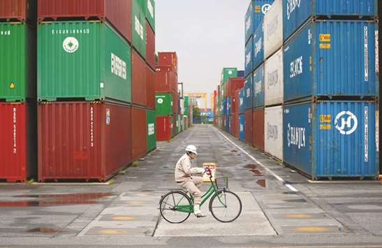 A worker rides a bicycle in a container area at a port in Tokyo. Japanu2019s exports to the US rose 13% in the year to November, led by cars and excavators, following a 7.1% gain in the previous month.
