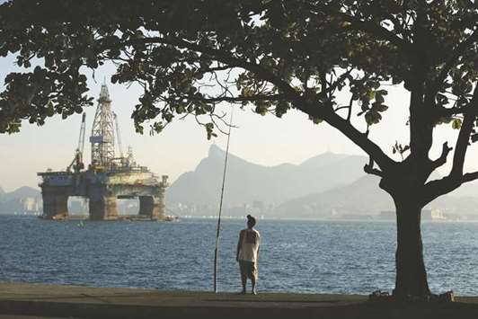 A man fishes in Guanabara Bay while an oil drilling platform floats in the background near Niteroi, Brazil (file). Statoil will make an initial payment of $2.35bn and as much as $550mn in contingent transfers for the Campos Basin field, which still holds recoverable resources of more than 1bn barrels of oil equivalent after producing since the 1990s, Statoil said in a statement yesterday.