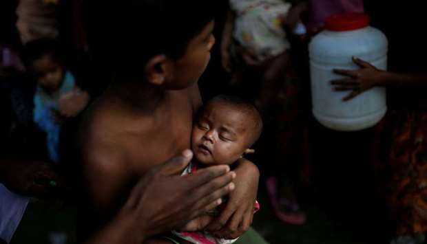 A boy holds a baby as Rohingya refugees wait to receive food supplies at a World Food Programme (WFP) distribution at the Balukhali refugee camp near Cox's Bazar, Bangladesh. Reuters