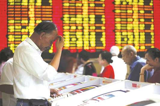 Investors look at computer screens showing stock information at a brokerage house in Shanghai. Chinese stock investors can expect a better performance next year as earnings growth picks up and MSCI Inc includes the countryu2019s equities in its benchmark indexes, according to the most accurate forecaster for 2017.
